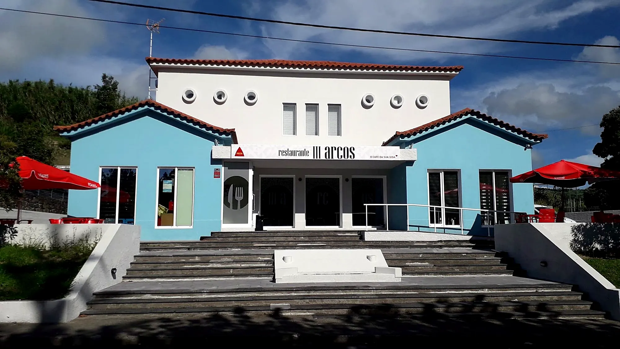Fassade des Restaurante III Arcos, ein weiß-blaues Gebäude mit Treppe, in Ginetes